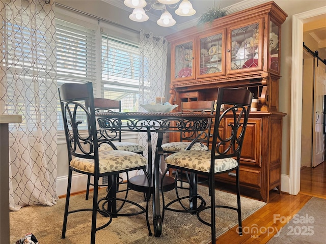 dining room with crown molding, light hardwood / wood-style floors, and a barn door