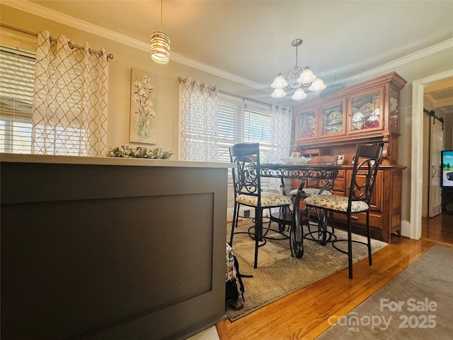 dining space featuring ornamental molding, hardwood / wood-style floors, and an inviting chandelier