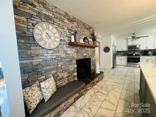 unfurnished living room with ceiling fan and a large fireplace