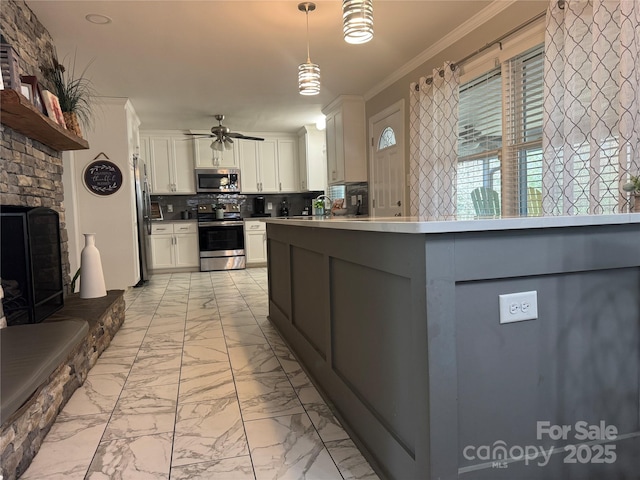 kitchen with crown molding, white cabinetry, hanging light fixtures, stainless steel appliances, and a large fireplace