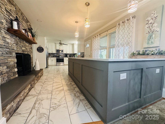 kitchen featuring a stone fireplace, hanging light fixtures, appliances with stainless steel finishes, ceiling fan, and white cabinets