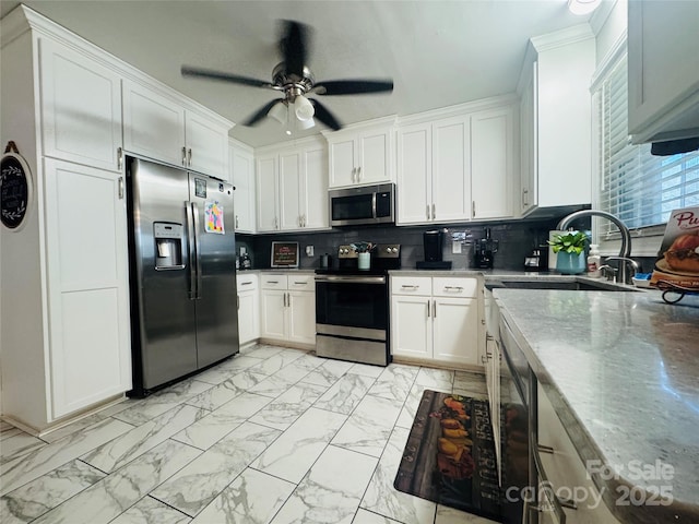 kitchen featuring sink, white cabinetry, ceiling fan, stainless steel appliances, and decorative backsplash