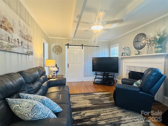 living room with crown molding, a fireplace, wood-type flooring, and a barn door