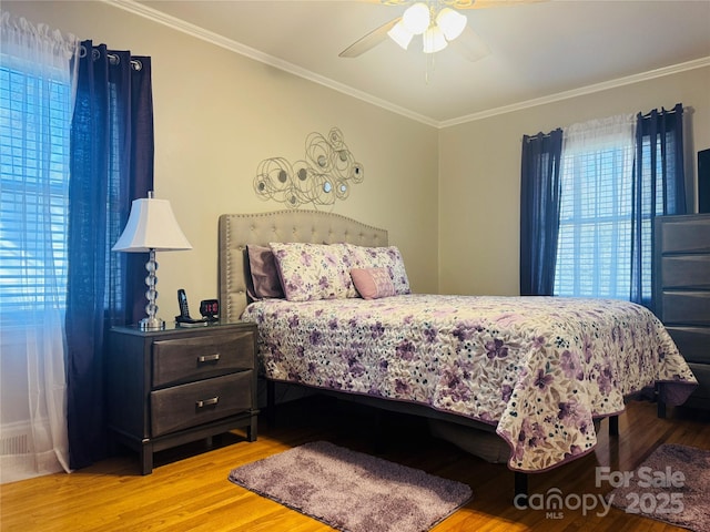 bedroom featuring light hardwood / wood-style flooring, ornamental molding, and ceiling fan