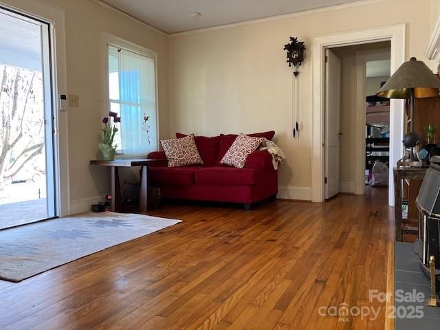 living room with ornamental molding, baseboards, and wood finished floors