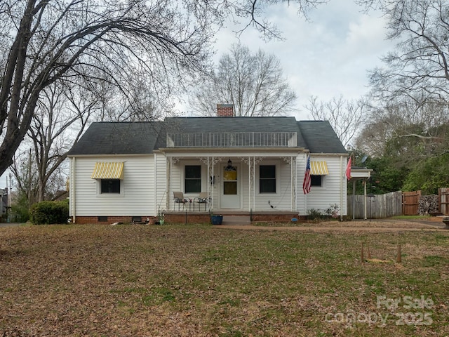 view of front facade featuring a front lawn, a chimney, fence, and a porch