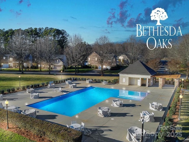 community pool featuring an outbuilding, a patio, fence, and a residential view