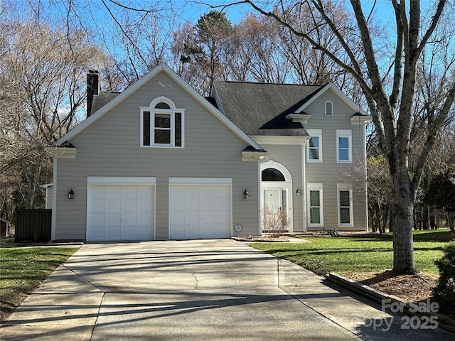 traditional home with a garage, driveway, a shingled roof, a chimney, and a front yard