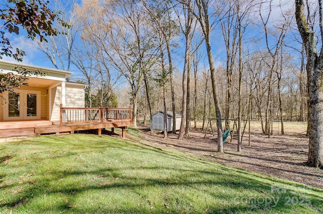 view of yard featuring a shed, a deck, a playground, and an outbuilding