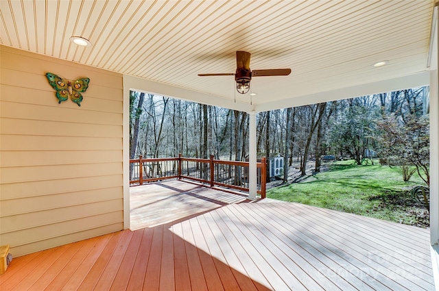 deck with a ceiling fan and a lawn