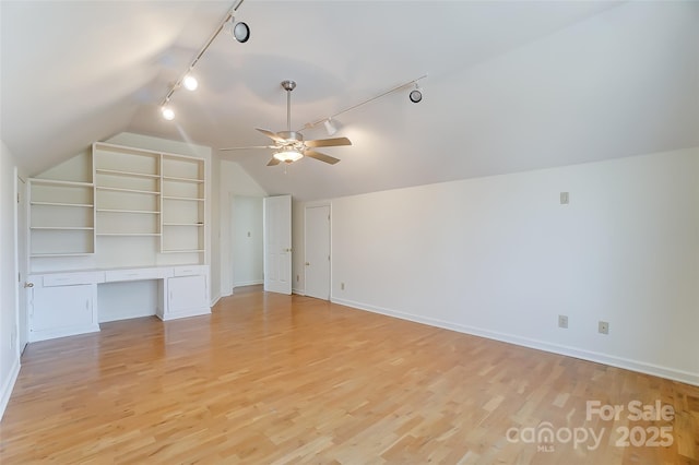 bonus room featuring light wood-style floors, vaulted ceiling, built in desk, and baseboards