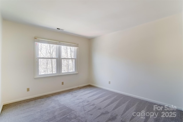 carpeted spare room featuring visible vents and baseboards