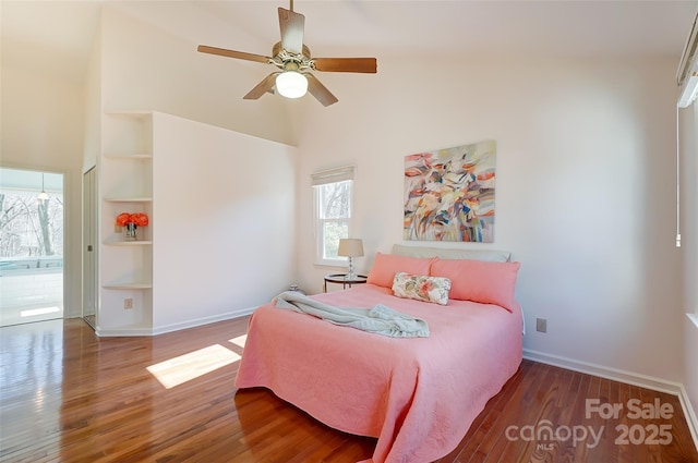 bedroom featuring a ceiling fan, dark wood finished floors, a towering ceiling, and baseboards