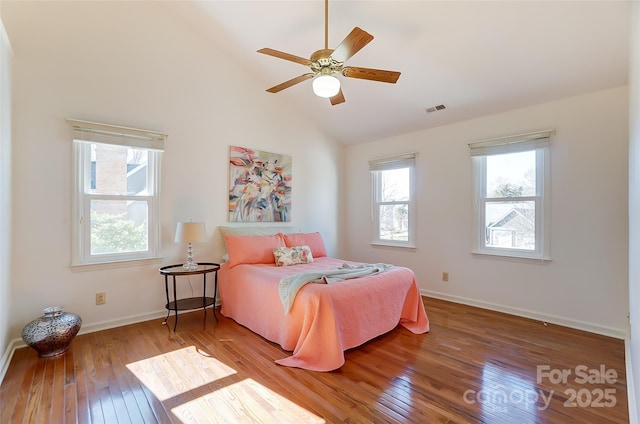 bedroom featuring baseboards, multiple windows, visible vents, and wood finished floors