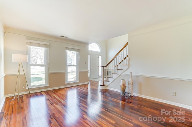 spare room featuring dark wood-style floors, baseboards, stairs, and visible vents