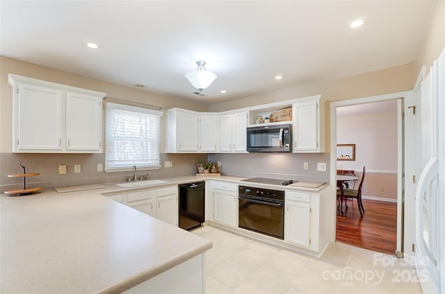 kitchen featuring light countertops, white cabinets, a sink, and black appliances