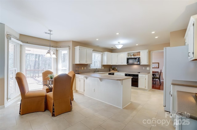 kitchen featuring black oven, stainless steel microwave, light countertops, and white cabinets