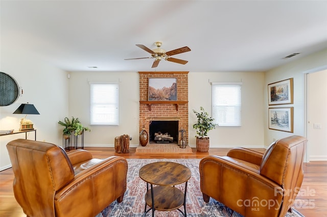 living area with a healthy amount of sunlight, light wood finished floors, a fireplace, and visible vents