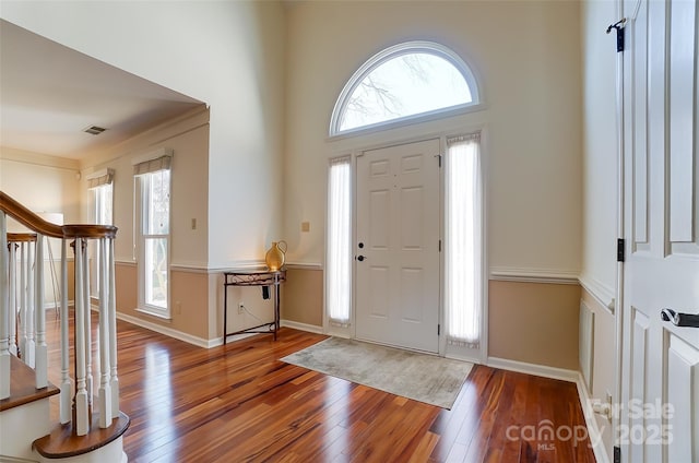 foyer entrance with baseboards, plenty of natural light, visible vents, and wood finished floors