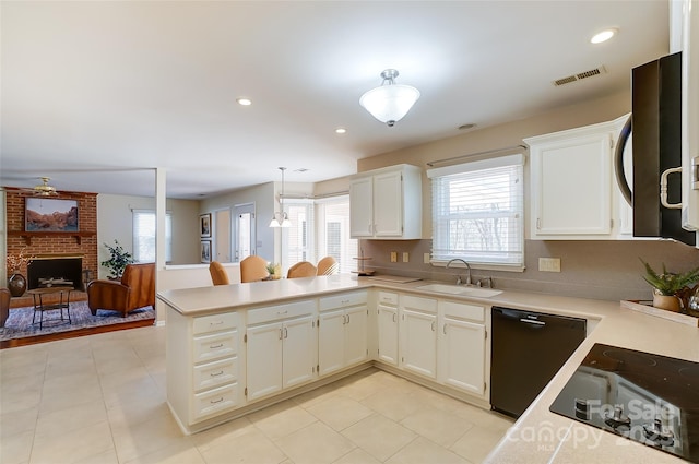 kitchen with a peninsula, a sink, visible vents, light countertops, and black appliances