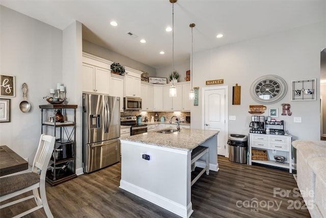kitchen with backsplash, a sink, light stone countertops, appliances with stainless steel finishes, and dark wood-style flooring