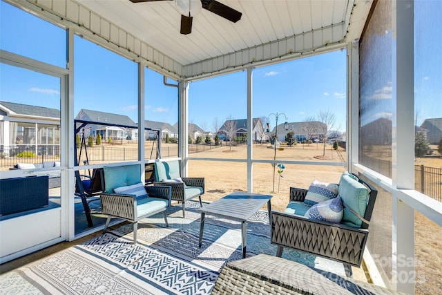 sunroom with a residential view, ceiling fan, and an outdoor living space