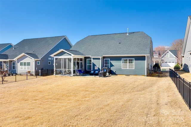 rear view of property featuring a fenced backyard, a sunroom, a yard, and roof with shingles