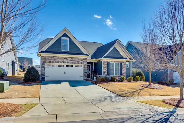 craftsman house with an attached garage, driveway, and stone siding