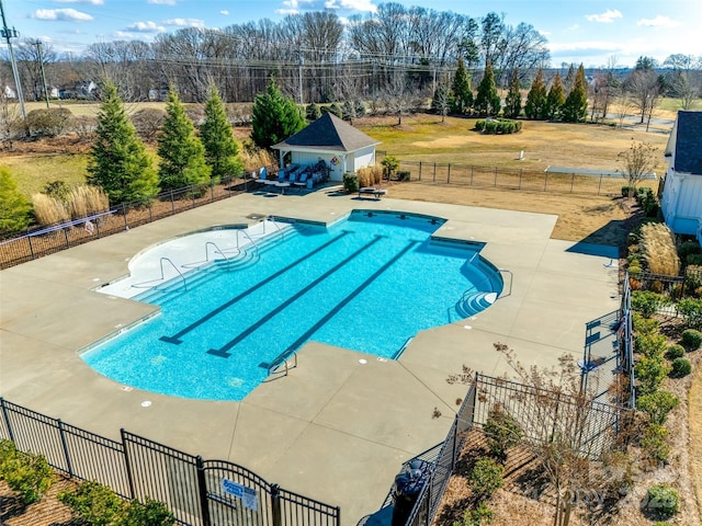 pool with fence, a patio area, an outbuilding, and an exterior structure