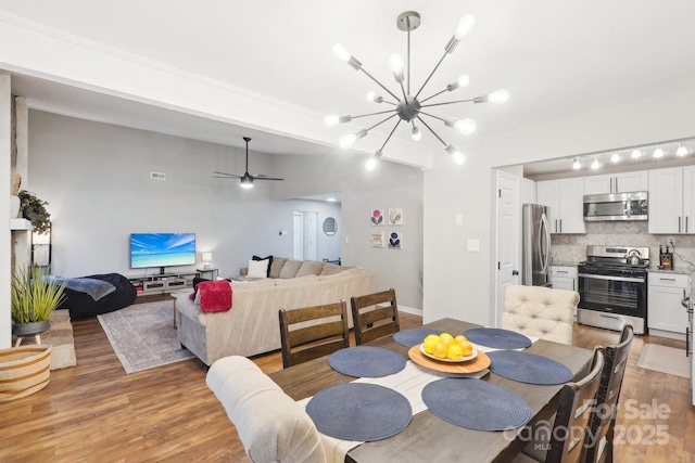 dining room with visible vents, light wood-style flooring, and ceiling fan with notable chandelier