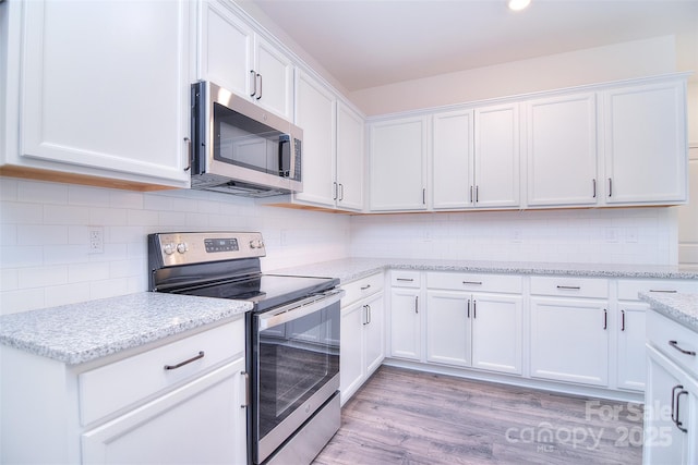 kitchen featuring white cabinets, light stone countertops, light wood-style flooring, and stainless steel appliances