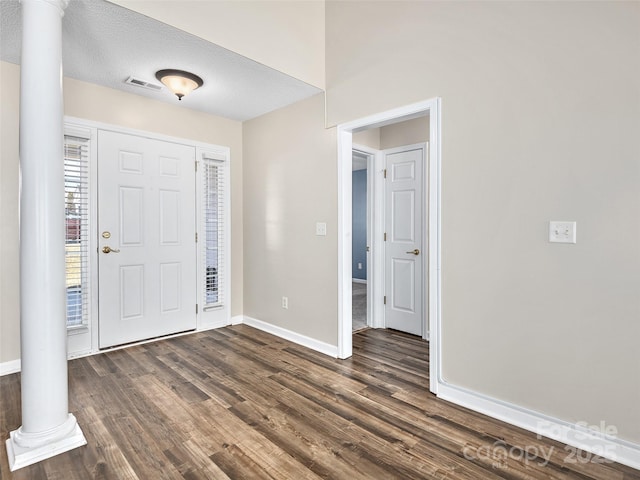 foyer entrance with decorative columns, dark hardwood / wood-style floors, and a textured ceiling