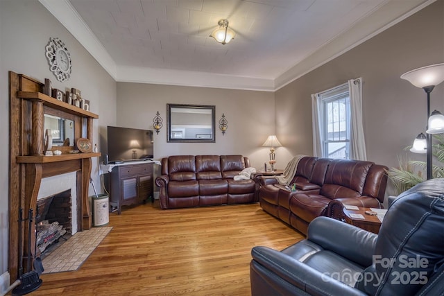 living room featuring a brick fireplace, crown molding, and light hardwood / wood-style flooring