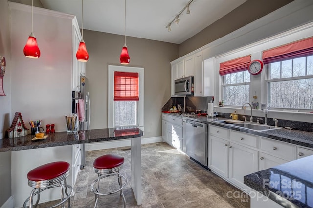 kitchen with appliances with stainless steel finishes, white cabinetry, a kitchen breakfast bar, and sink