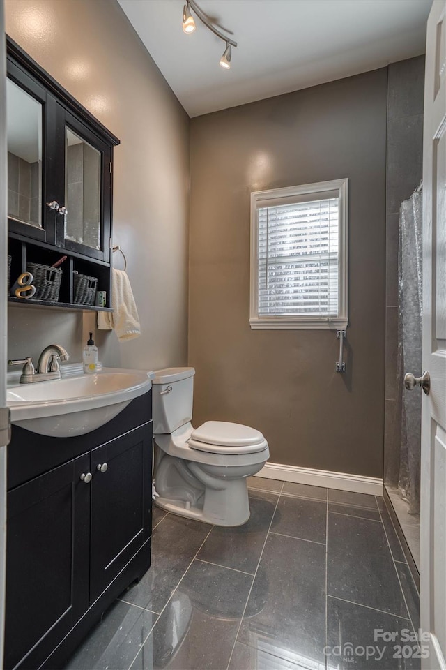 bathroom with toilet, track lighting, and vanity