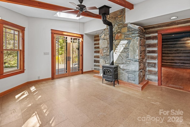 14 Woods Rd, Fairview, NC 28730 - unfurnished living room featuring a wood stove, ceiling fan, healthy amount of natural light, beam ceiling, and french doors