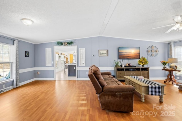 living room featuring lofted ceiling, light wood-type flooring, and a healthy amount of sunlight