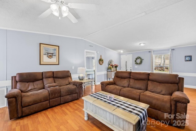 living room with vaulted ceiling, light wood-type flooring, and ornamental molding