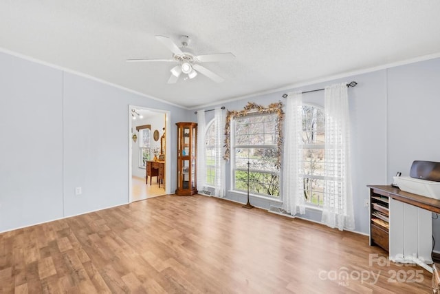 interior space with ornamental molding, a textured ceiling, ceiling fan, and hardwood / wood-style flooring