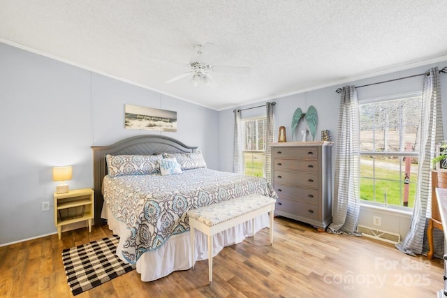 bedroom featuring ceiling fan, a textured ceiling, crown molding, and light wood-type flooring