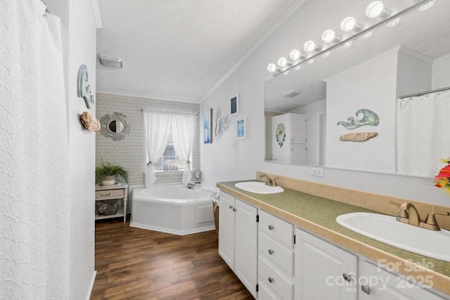 bathroom with a washtub, wood-type flooring, vanity, and ornamental molding