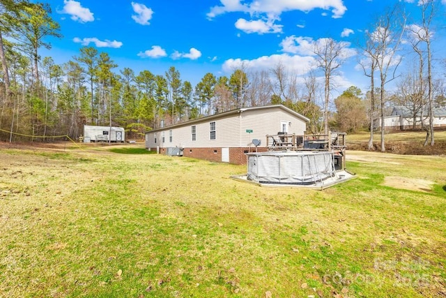 rear view of property featuring a swimming pool side deck and a yard