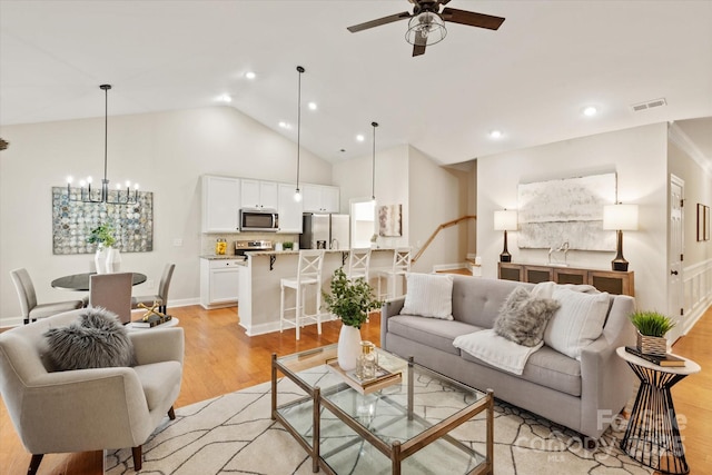 living area featuring visible vents, stairs, ceiling fan with notable chandelier, light wood-type flooring, and recessed lighting