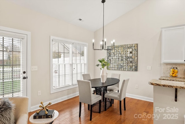 dining room with lofted ceiling, light wood-style floors, visible vents, and baseboards