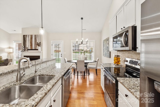 kitchen featuring white cabinetry, appliances with stainless steel finishes, pendant lighting, and a sink