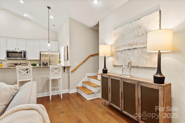 interior space with baseboards, stairway, light wood-type flooring, high vaulted ceiling, and recessed lighting