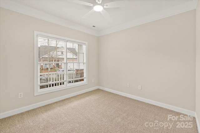 spare room with a ceiling fan, carpet, baseboards, and crown molding