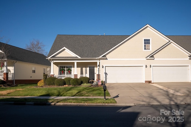 view of front of home with a garage, a front yard, covered porch, and concrete driveway