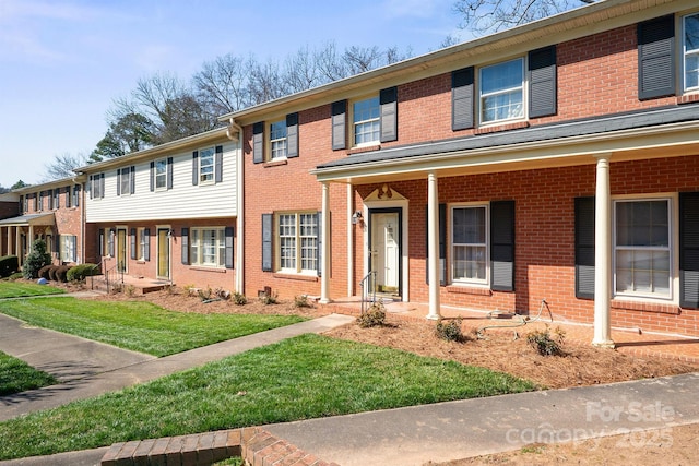 townhome / multi-family property with a front yard and brick siding