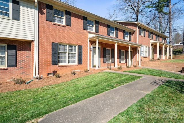 view of front facade with covered porch, brick siding, crawl space, and a front lawn